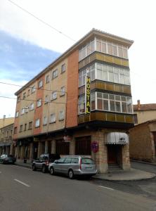 un bâtiment avec des voitures garées devant lui dans l'établissement Hostal Romi, à Cantalejo