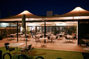 a patio area with tables, chairs and umbrellas at Sundowner Motel Hotel in Whyalla
