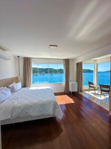 een slaapkamer met een bed en uitzicht op het water bij Pousada Atalaia Boutique FR in Arraial do Cabo