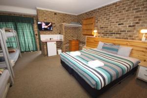 a bedroom with a bed and a brick wall at Acacia Snowy Motel in Jindabyne