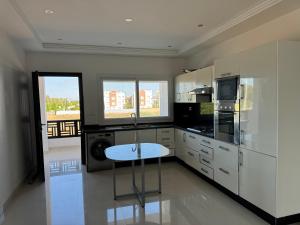a kitchen with white cabinets and a stool in it at 2 Bedroom Apartment for Families in Saidia 