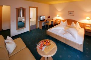 雷西亚Hotel Am Reschensee的一间配有床、沙发和桌子的酒店房间