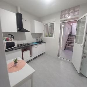 une cuisine avec des armoires blanches et une table à l'intérieur dans l'établissement Clavelina Economy Room calle Julio Antonio, à Alicante