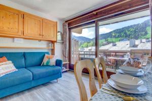 a living room with a blue couch and a table with chairs at Sunny central studio in Morzine