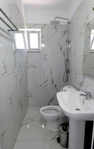 a white bathroom with a toilet and a sink at Franko in Delvinë