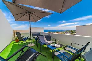 un patio con sillas y una sombrilla en el balcón en La Punta, en Alcalá
