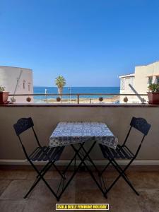 Una mesa y dos sillas en un balcón con vista al mar. en Isola delle Femmine Holiday, en Isola delle Femmine