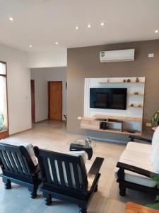 Una sala de estar con sillas y un televisor de pantalla plana. en Finca La Candelaria, en Santiago del Estero