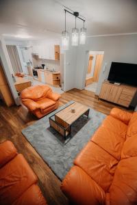 a living room with an orange couch and a table at Platz Apartman in Văleni