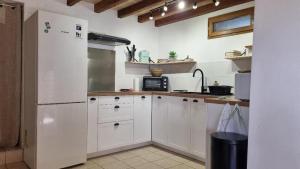 a kitchen with white cabinets and a white refrigerator at Gîte et chambres d'hôtes Aux Charlots in Lagarde-Hachan +8 photos