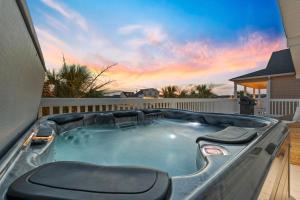 a hot tub in a backyard with a sunset in the background at Channel Vibes in Myrtle Beach