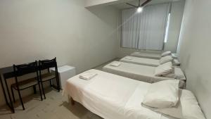 a bedroom with two beds and a chair and a mirror at Hotel Aquarius in Coronel Fabriciano