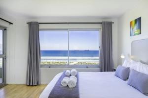 a bedroom with a bed and a large window with the ocean at Sea Spray B306 in Bloubergstrand +27 photos