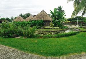 a resort with grass huts and a pond at Charmant appartement central avec jardin privé in Papeete