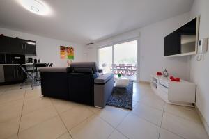 a living room with a black couch and a kitchen at Magnifique T3 proche de la plage in Calvi
