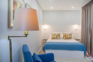 a bedroom with a bed and a blue chair at Casa do Senhor do Colégio in Ponta Delgada