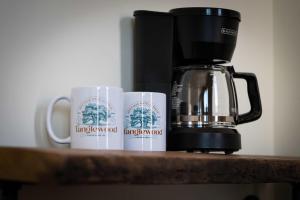 Dos tazas de café en un mostrador junto a una cafetera. en Courtyard King - Room 4, en Versailles