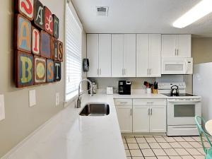 a kitchen with white cabinets and a sink at Latitude Adjustment A in Tybee Island