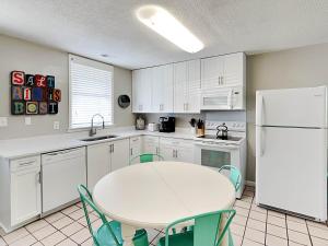 a kitchen with a table and a white refrigerator at Latitude Adjustment A in Tybee Island +10 photos