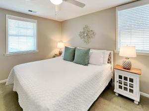 a bedroom with a white bed and two windows at Latitude Adjustment A in Tybee Island