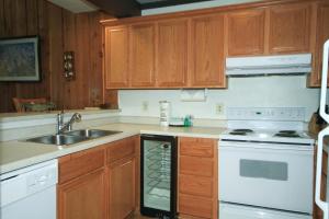 une cuisine avec des armoires en bois, un évier et une cuisinière dans l'établissement Mammoth Ski & Racquet Club #120 = Pet Okay!, à Mammoth Lakes