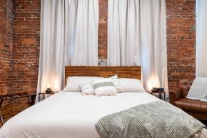 Un dormitorio con una cama blanca y una pared de ladrillo. en ADA Suite - Room 6, en Versailles