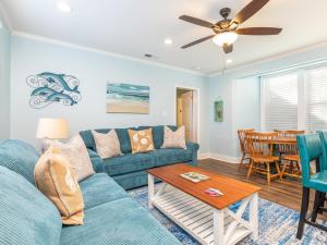 a living room with a blue couch and a table at Walkin On Sunshine in Tybee Island