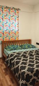 a bed with a black and white comforter in a bedroom at Sharia homestay in Kodaikānāl +12 photos