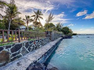 a stone retaining wall next to the water with palm trees at Greenyvilla in Calodyne