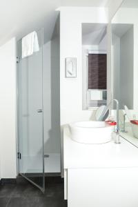 a white bathroom with a sink and a shower at Hôtel Ar Iniz in Saint Malo
