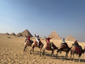 a group of people riding on camels in front of pyramids at sphinx one centre hotel in Cairo