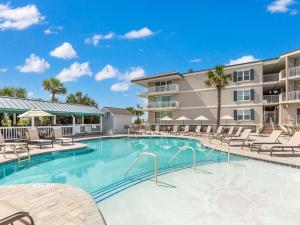 a swimming pool with chairs and a building at The Vue 226 in Tybee Island