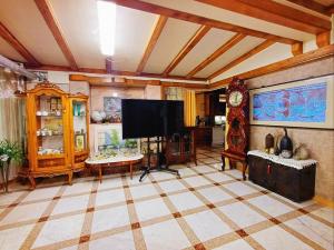 a living room with a flat screen tv and a clock at The Red Brick Grove in Wonju