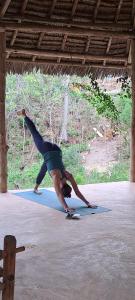 a person doing a handstand on a yoga mat at yasmin ecohouse zanzibar in Kizimkazi
