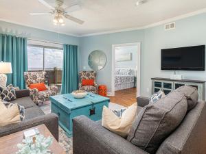 a living room with a couch and a tv at Sandpiper 203 in Tybee Island