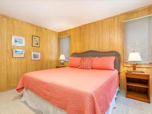 a bedroom with a bed with orange sheets and wooden walls at Ocean Walk in Tybee Island