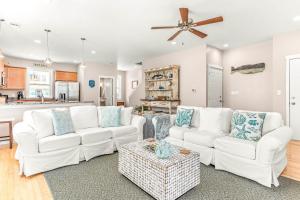 a living room with white furniture and a ceiling fan at Peach Coral in Tybee Island