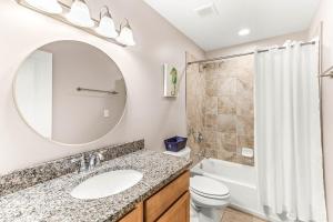 a bathroom with a sink and a toilet and a mirror at Peach Coral in Tybee Island +24 photos