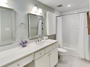a bathroom with a sink and a toilet and a mirror at Oceanside Unit A in Tybee Island +31 photos