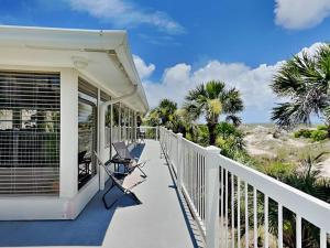 a porch of a house with chairs and palm trees at Oceanside Unit A in Tybee Island
