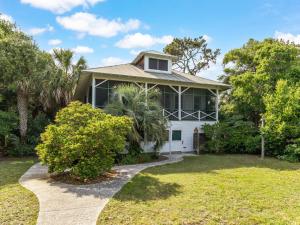 a white house with a palm tree in front of it at Ocean Oasis in Tybee Island