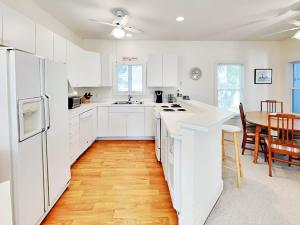 a kitchen with white cabinets and a wooden floor at Mercy Me in Tybee Island