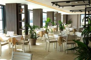 a restaurant with white tables and chairs and plants at Joelle Premium Hotel in Sarandë
