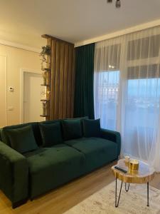 a living room with a green couch and a table at Apartament Central Arad AFI 2 camere Ared in Arad