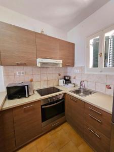 a kitchen with wooden cabinets and a sink and a microwave at Corfu Glyfada Beach Apartment 49 in Corfu