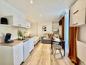 a kitchen and living room with a table and a couch at Studio 3 - Cinéma Sport Parking - DABNB in Limoges