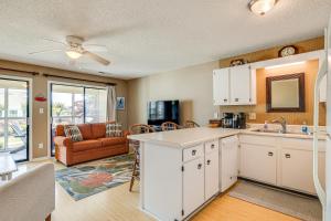 a kitchen with white cabinets and a living room at Emerald Isle Condo Near Beach with Screened Porch! in Emerald Isle