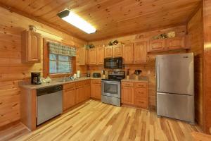 eine Küche mit Holzschränken und einem Edelstahlkühlschrank in der Unterkunft Live, Laugh, Love Pool Lodge in Cosby