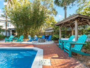a pool with blue chairs and a gazebo at Guiding Light Cottage in Tybee Island