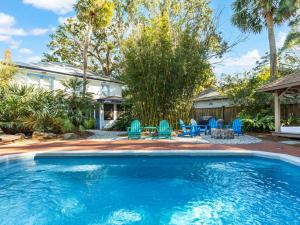 a swimming pool with blue chairs and a house at Guiding Light Cottage in Tybee Island